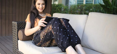 A woman sitting reading a book using black and yellow harem pants